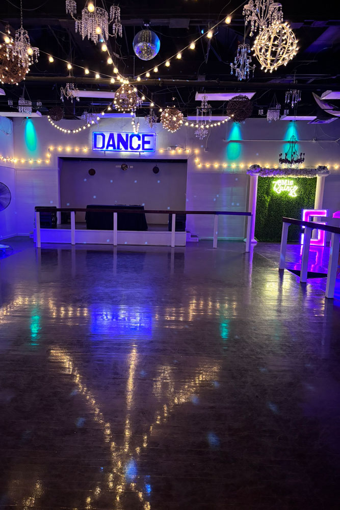Spacious dance floor and bar area under chandeliers at a corporate event venue