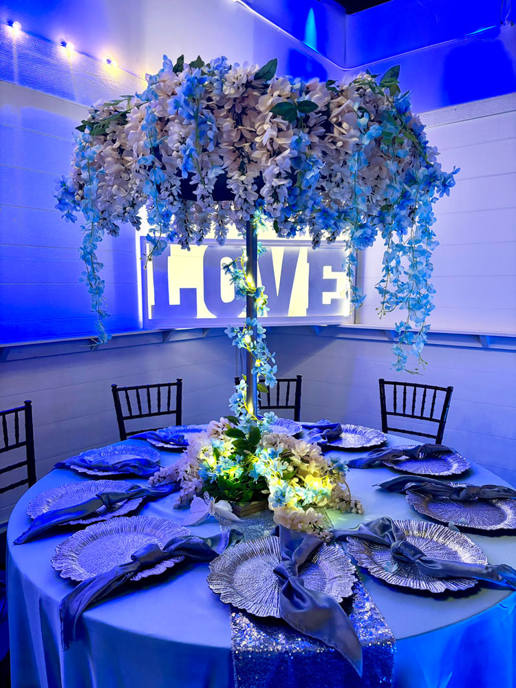 Reception centerpiece designed with layered blue hues, greenery and soft candlelight