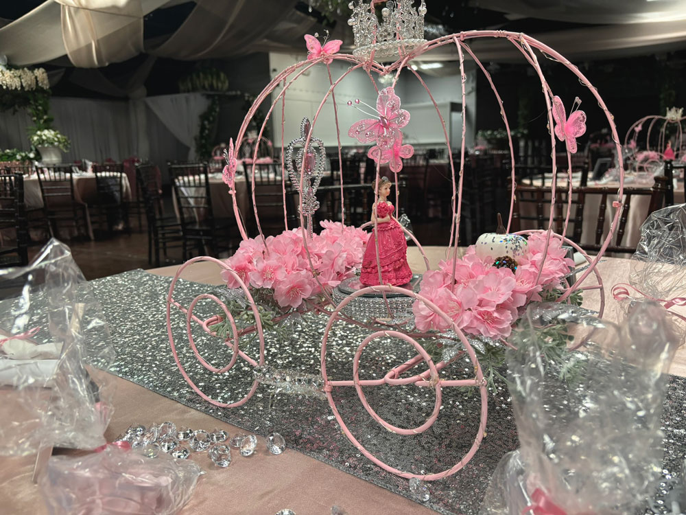 Elegant Cinderella-inspired quinceañera ccoach centerpiece with formal table settings and soft romantic lighting
