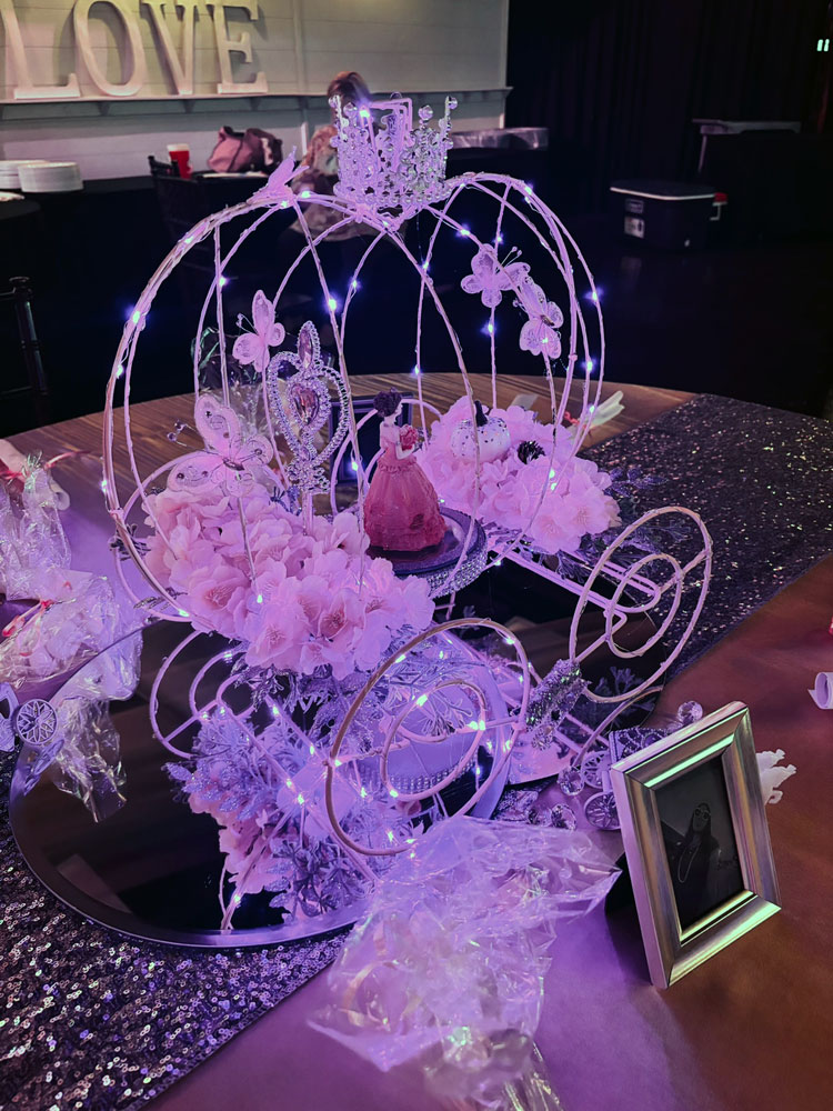 Cinderella-style quinceañera coach centerpiece featuring dramatic details, lighting, and elegant design