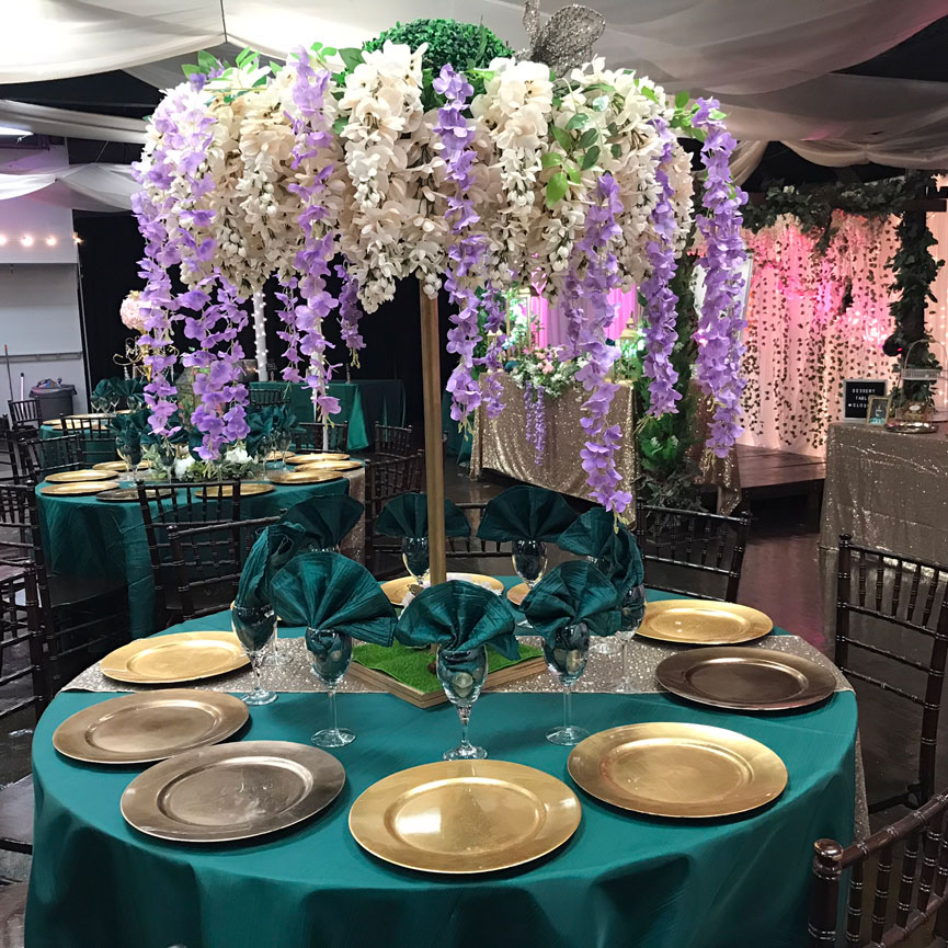 Table centerpiece featuring lush foliage, florals, and warm candlelight