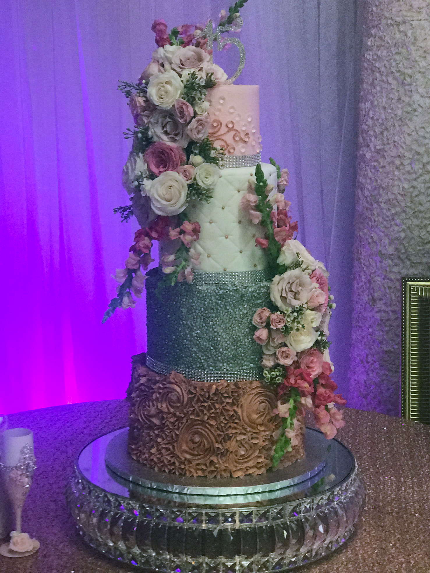 Cake on cake table accented with soft pink florals and elegant decor
