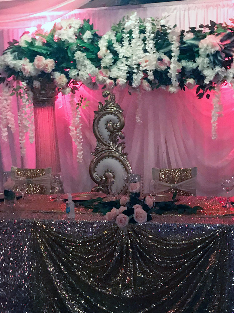 Head table styled in blush pink with floral arrangements and soft lighting