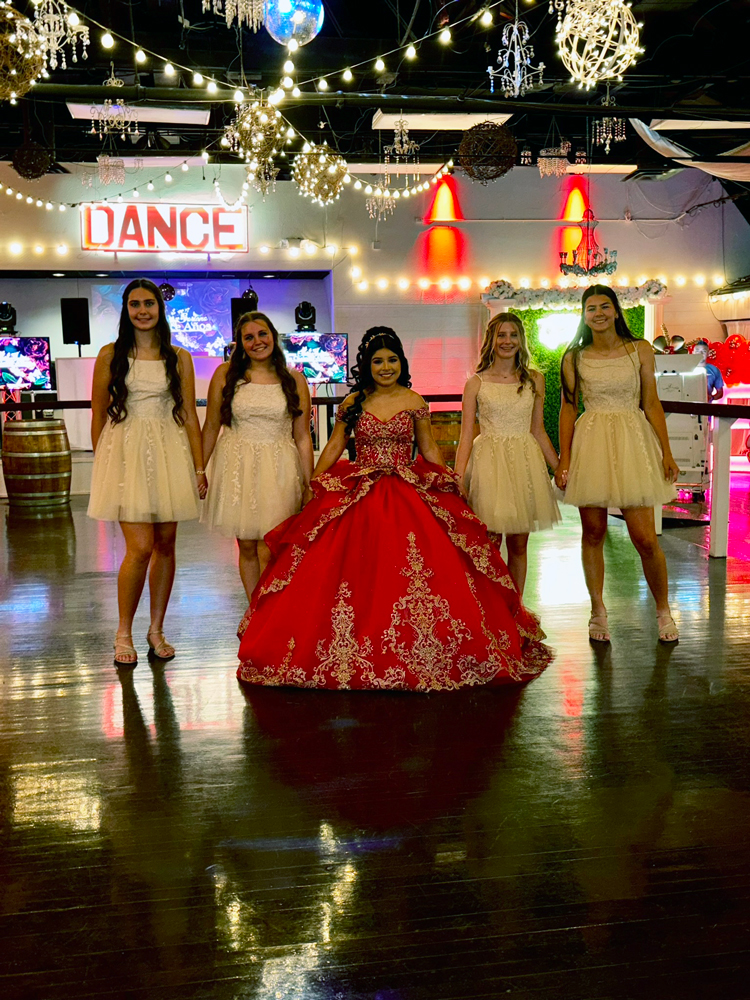 Quince girl sharing her celebration with friends framed by rich red uplighting