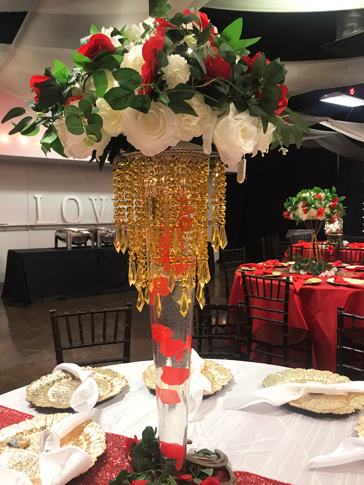 Guest table with tall jeweled floral centerpiece styled in layered shades of red