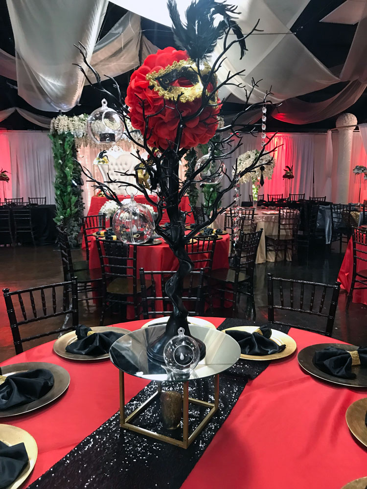 themed masquerade ball centerpiece in a glass vase with accent lighting
