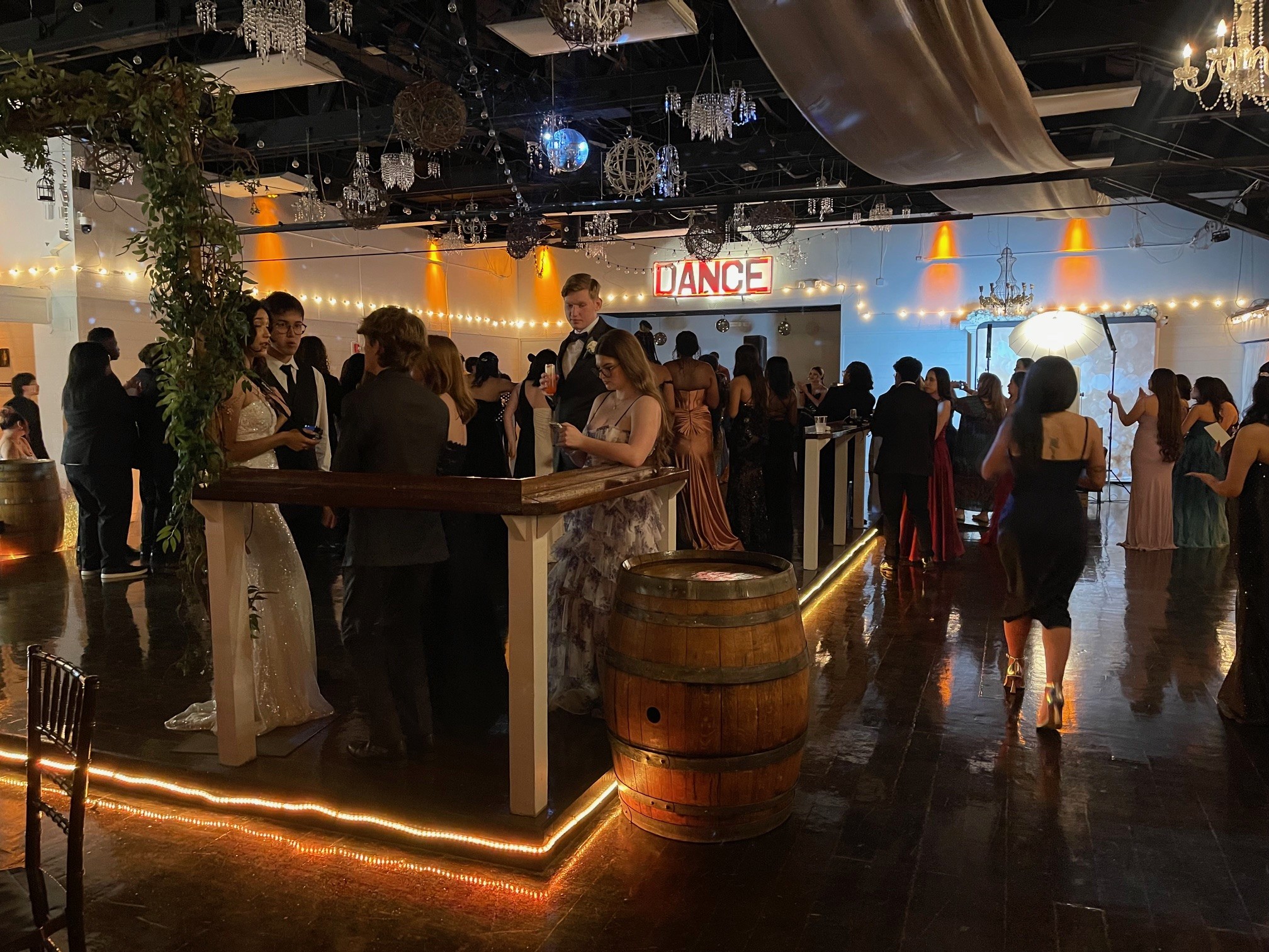 Prom attendees socializing and dancing on the illuminated dance floor.