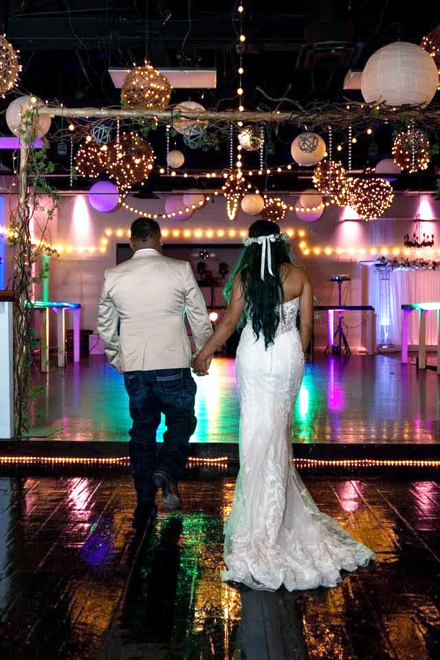 Bride and groom heading to illuminated dance floor for first dance.