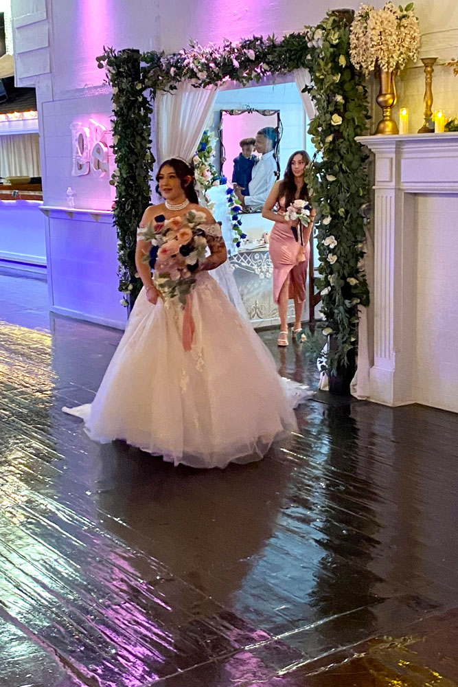 Bride making her entrance toward the ceremony garden gazebo.