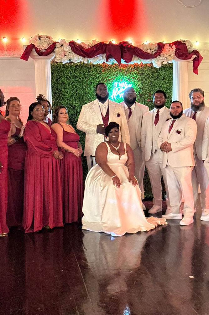 Bride and groom with family and friends posing for family portrait.