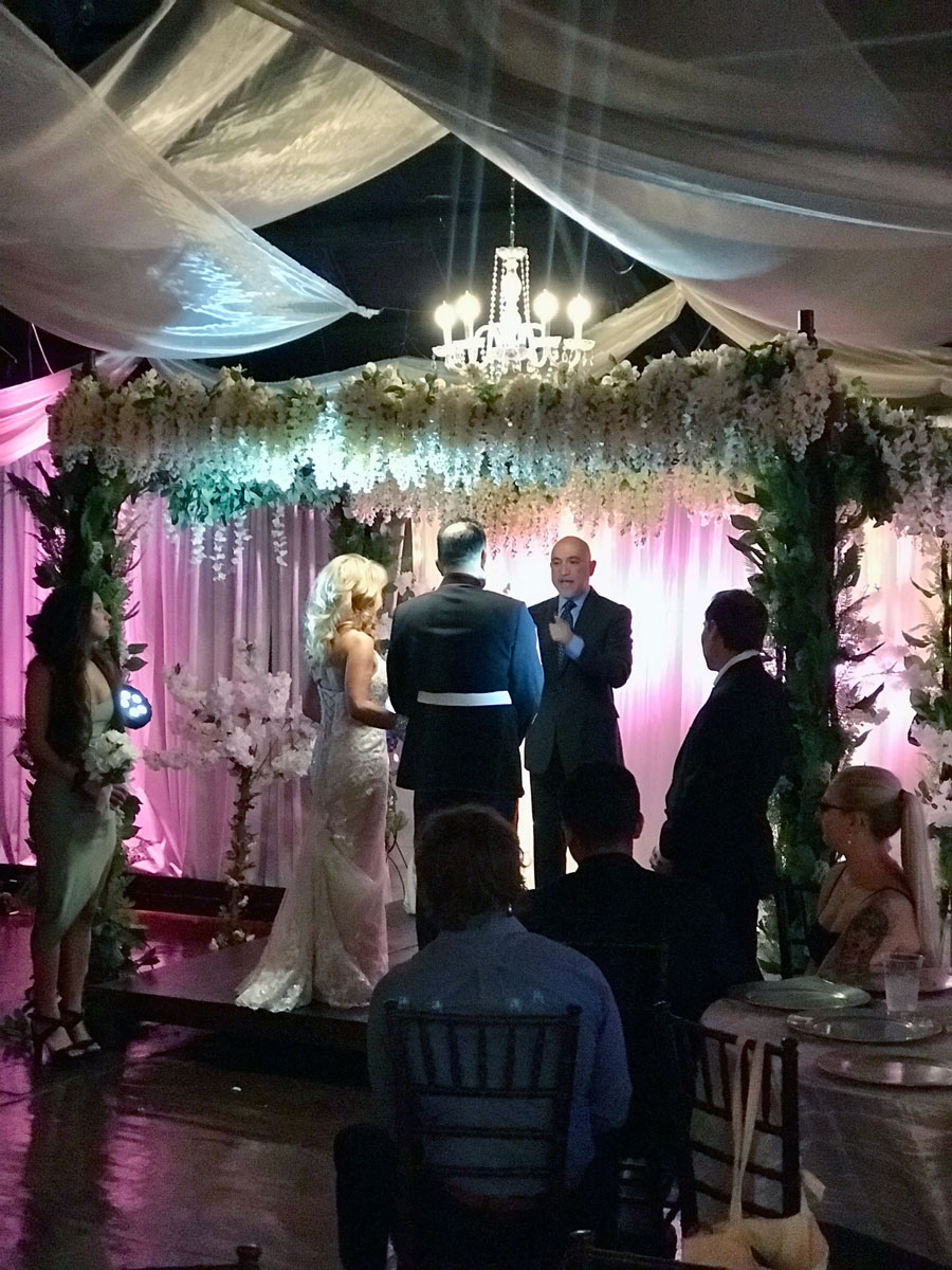 Bride and groom saying vows on garden gazebo ceremony stage.
