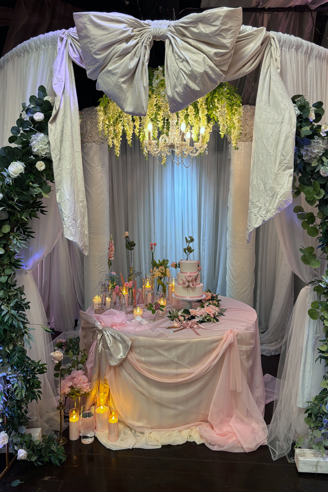 cake table with greenery, floral decor, and lots of candles