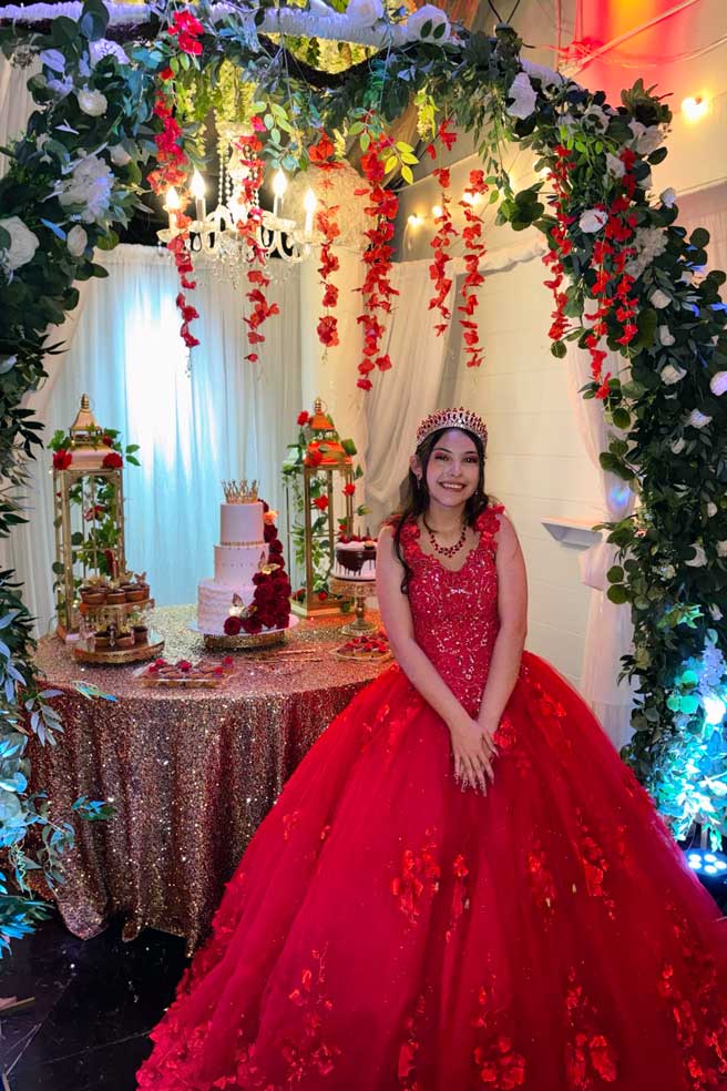 Quinceañera taking a photo op monent in front ofthe  beautiful cake table at a Fort Worth event venue