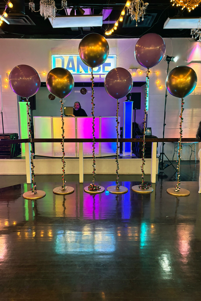 DJ set up on the stage beside the illuminated dance floor.