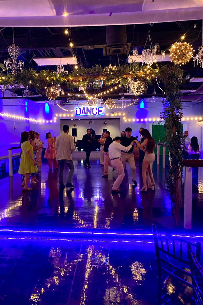 Crowded dance floor with colorful uplighting and energetic celebration