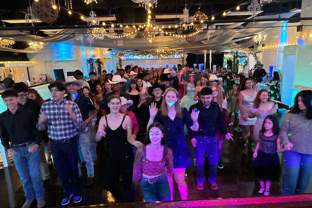 Crowd dancing on the illuminated dance floor with festive lights