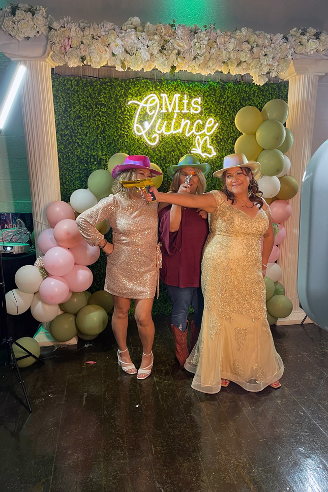 Guest stopping for a photo op moment at the floral and greenery wall right beside the dance floor